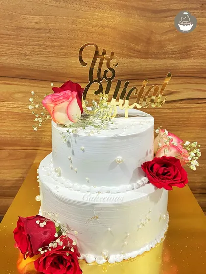 I believe every love story deserves a beautiful cake. This is a two-kilogram, two-tier Dutch Truffle engagement cake, decorated with fresh roses and baby's breath to mark the couple's special "It's Official!" moment.