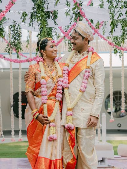 A portrait of the couple during their Muhurtham. The bride's Kanjeevaram saree and the groom's veshti are complemented by beautiful lotus garlands, a key element of our floral design.