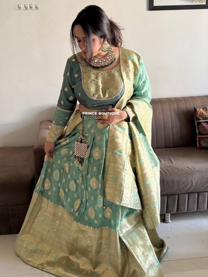 This sage green Banarasi silk lehenga is pure elegance. The rich woven fabric with gold motifs and a heavy border gives it a luxurious and traditional feel.