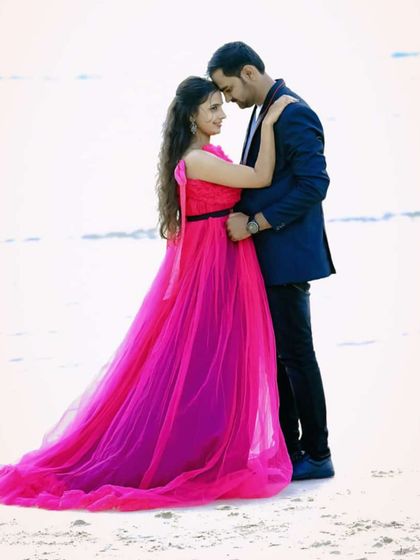 A classic romantic pose on a white sand beach. The two-tone pink and magenta gown flows beautifully, creating a dreamy and colorful pre-wedding photo.