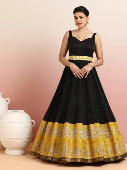 Elegance in every detail. This black pleated gown-style lehenga with its rich golden zari border exudes timeless sophistication. It is a perfect blend of modern chic and traditional artistry.