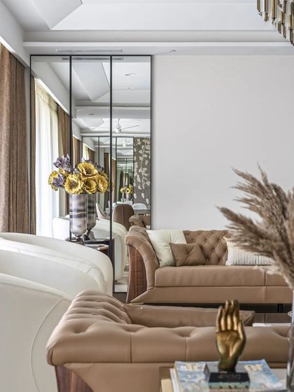 A detail shot focusing on the soft textures and forms within the living room, from the curved armchair to the plush cushions and dried pampas grass arrangement.