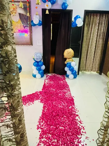 A home entrance decorated with a rose petal pathway and 'Baby Boy' balloon pillars.