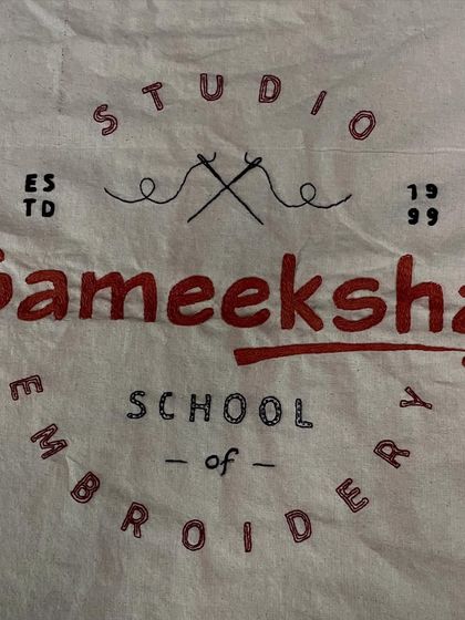 A close-up of the hand-embroidered Sameeksha logo. The different stitches used for the lettering and design reflect the variety of techniques we teach.