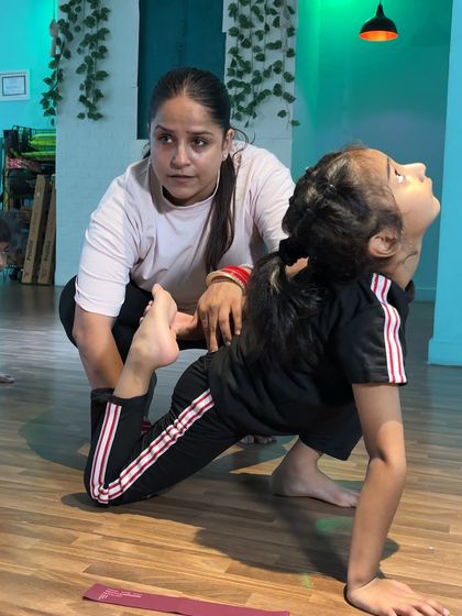 Guiding a student through a lunge and backbend, I focus on opening up her chest and shoulders while protecting her lower back. This hands on guidance is crucial for mastering advanced flexibility poses safely.