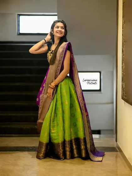 A vibrant half-saree in parrot green and royal purple, draped elegantly for a modern traditional look. This shot captures the full, flowing silhouette.