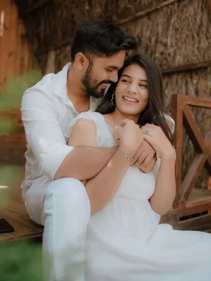 A moment of pure, uninhibited laughter on a rustic wooden porch. Dressed in coordinated white, this couple's joy is infectious, showcasing a perfectly candid moment from their pre-wedding shoot.