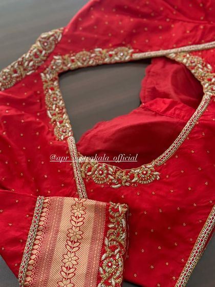 A classic red bridal blouse with a beautifully embroidered neckline and sleeves. The design uses zardosi and stone work for a traditional yet elegant feel.