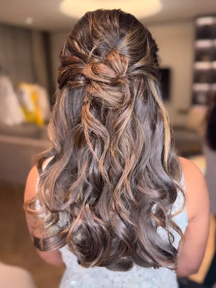 A beautiful half-updo with a knotted detail and soft waves, on highlighted hair.