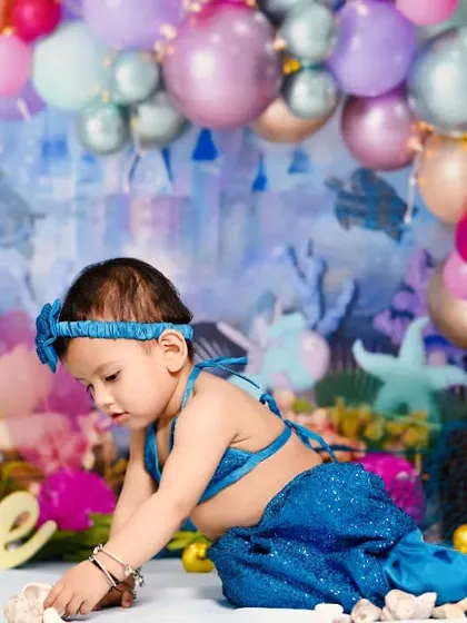 This little mermaid is exploring her under-the-sea kingdom. I designed this entire set with a castle backdrop, colorful balloons, and seashells for her first birthday.