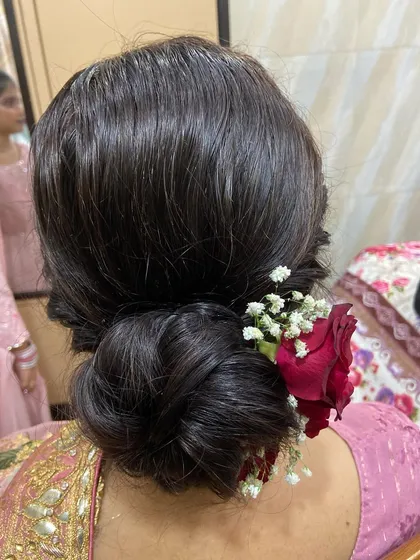A simple yet beautiful low bun with a single rose and a sprinkle of baby's breath for a touch of elegance.