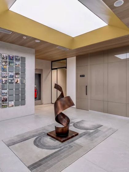 The entrance lobby features a striking spiral sculpture and a digital art wall, immediately communicating the firm's innovative spirit. The design uses a neutral palette, allowing the art and architectural forms to stand out.