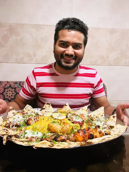 A happy customer poses with a massive chicken thaal, showcasing the generous portions and variety that make my platters a favorite for group dining.