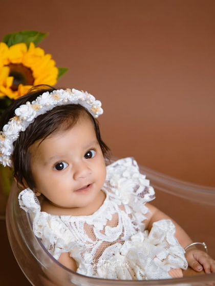 A close-up portrait of the baby girl, highlighting her beautiful eyes and floral headband.