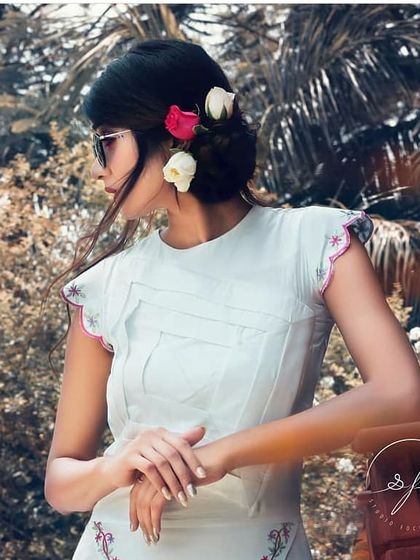 A closer look at the styling for the 'Passage to India' shoot. The simple white dress with pin-tuck details is accessorized with fresh flowers in the hair, creating a look that feels both modern and deeply connected to nature.