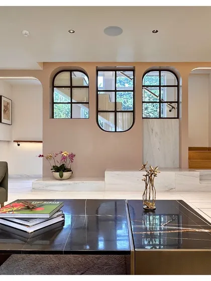 From the main living area, the arched windows on the mezzanine level act as internal balconies, enhancing the sense of openness and connection between floors. The soft pink wall color adds a gentle warmth to the space.