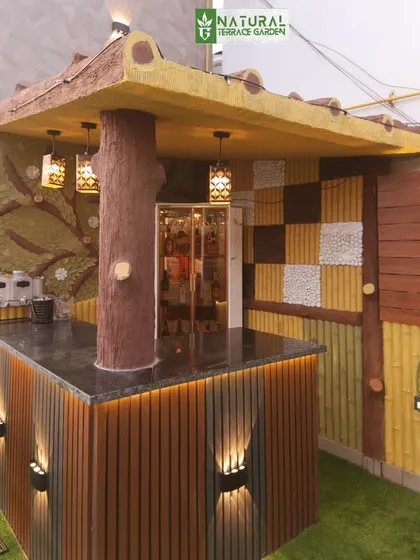 A whimsical, rustic-style bar completed in Shahdara, New Delhi. It features a tree-trunk support column and a colorful mosaic backsplash.