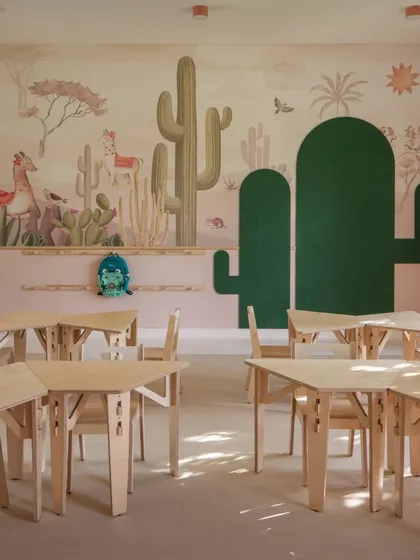 We created distinct, immersive worlds for each kindergarten level. This is a glimpse into the desert-themed classroom, where soft peach tones, cactus-shaped pinup boards, and beautiful wall murals create a warm and cohesive environment. The modular birch ply furniture allows for flexible learning setups, moving away from traditional plastic options.