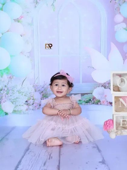 A full view of the enchanting fairy-themed photoshoot, with a baby girl smiling sweetly. The pastel balloons and floral arrangements create a dreamy and beautiful scene.