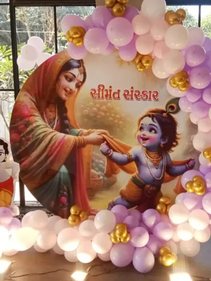 A traditional 'Shrimant Sanskar' baby shower decoration. This setup features a custom backdrop of Yashoda and baby Krishna, surrounded by a beautiful balloon ring in pastel purple and white with gold accents.