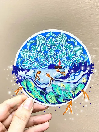 An ocean-themed mandala that captures the feeling of freedom. The design features waves, fish, and a sunset, all contained within a circular piece with a large mandala pattern in the sky.