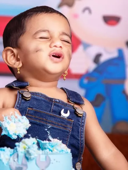 The pure, unadulterated joy of tasting cake for the first time! A perfect capture of a happy moment during a mechanic-themed cake smash.