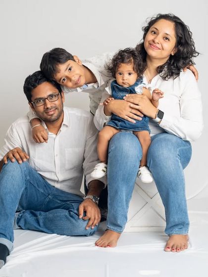 A relaxed and happy family portrait against a clean white backdrop. This timeless "jeans and white shirt" look keeps the focus entirely on your family's connection and smiles.