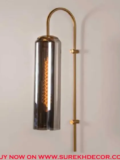 This elegant columnar wall lamp features a dusky, smoked glass shade for a more subdued and modern look. The antique brass finish provides a beautiful contrast, creating a sophisticated and moody light fixture.