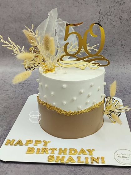 A stylish boho cake for a 50th birthday. The two-tone design is decorated with dried botanicals and a gold sprinkle fault line.
