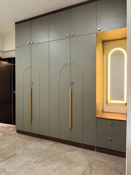This wardrobe connects with your personal style. We used a curved groove pattern on the shutters, filled with a contrasting paint color, and paired it with an arched, backlit dressing mirror.