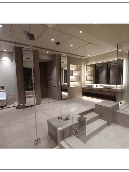 A different angle of the spa bathroom, showing the spacious layout that includes a walk-in glass shower, a separate toilet area, and the central jacuzzi tub, all designed with clean lines and natural stone finishes.