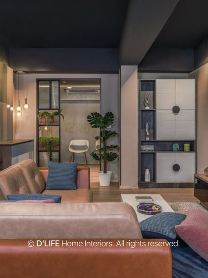 This living room features a warm, inviting design with a tan leather sofa, dark wood accents, and a unique teal chevron-patterned wall behind the bookshelf.