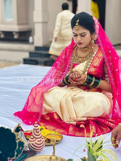 A bride during her puja ceremony. This look features a bright pink veil over a traditional saree, with makeup that is both sweat proof and long lasting.