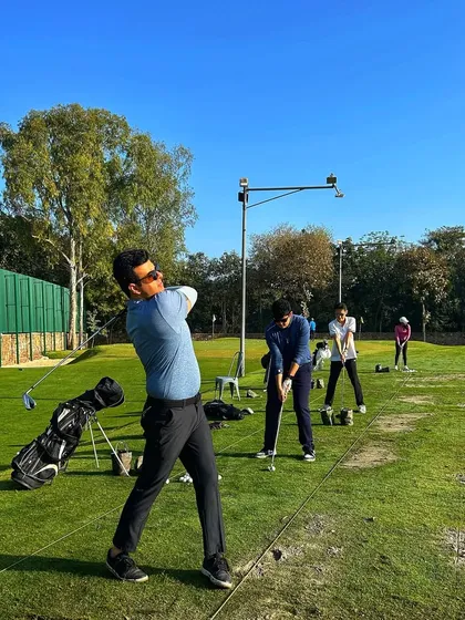 A golfer executes a powerful follow-through on a clear, sunny day on the range.