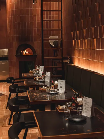 The inviting interior of our Forum Kanakapura Road outlet, with tables set and the brick oven glowing in the background.