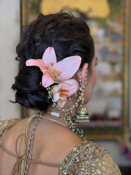 A slightly different angle of the lily-adorned messy bun, showing the intricate twists and the secure placement of the fresh flowers.