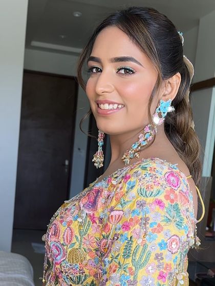 A happy client with a chic ponytail and face-framing highlights, ready for her carnival-themed event.