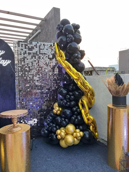A detailed shot of the unique balloon arrangement, designed to look like a Christmas tree with a gold chain garland, for the black and gold party.