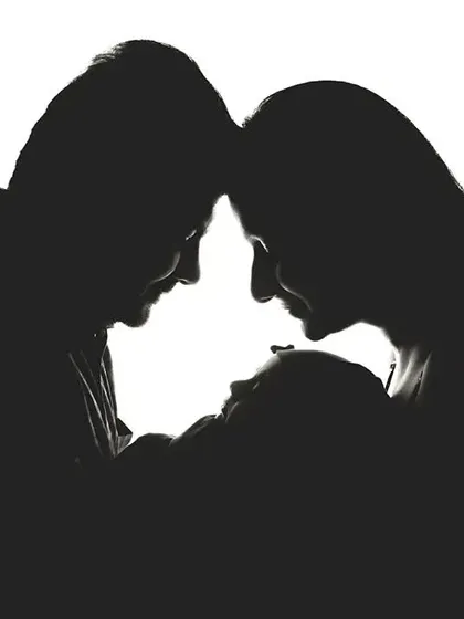 An artistic silhouette portrait of new parents holding their newborn baby, creating a timeless and emotional image. This style focuses on form and connection, offering a different perspective on family portraits.