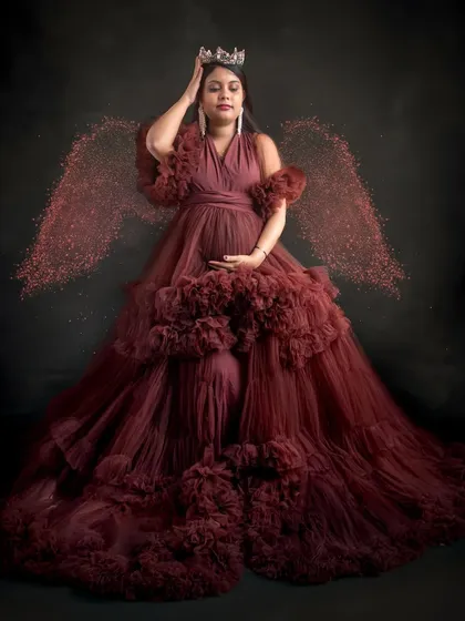 A truly ethereal portrait. The mom-to-be is wearing a crown and a stunning ruffled gown, with sparkling angel wings added for a touch of magic.