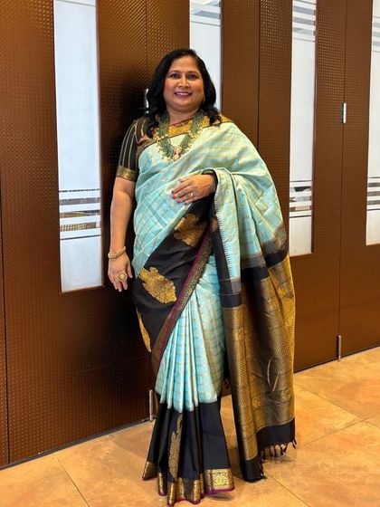 Our client Veena in a designer silk saree with a breathtaking combination of light blue and black.