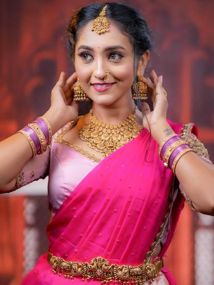 A beautiful close-up shot of the model adjusting her jhumkas, highlighting the earrings and the texture of the necklace.