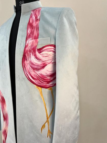 A side view of the flamingo sherwani, showing how the bird's body is painted to look as if it's gracefully standing on one leg.
