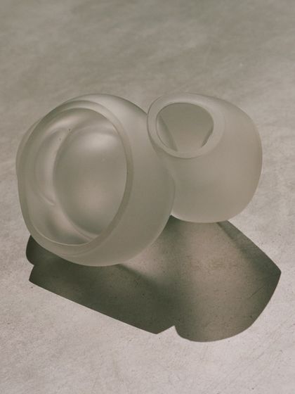 A still life of two frosted glass pendants from the Bocci 100 series, their soft, sculptural forms highlighted by the play of light and shadow.