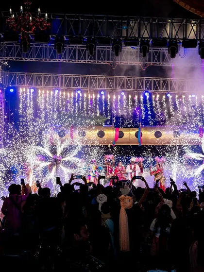 A wide shot of the Radha-Krishna themed varmala, with the entire stage lit up by spectacular floral-shaped fireworks, creating a truly divine and explosive celebration.
