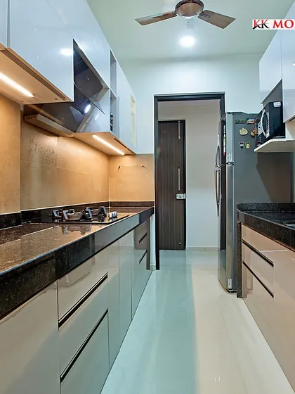 A beautiful parallel modular kitchen with a glossy laminate finish and granite countertops. The design makes the best use of a narrow space, providing ample storage and a clean, modern look.