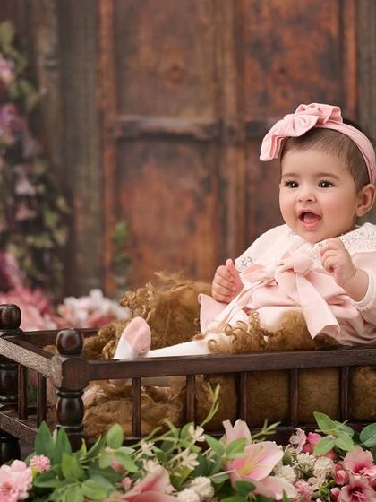 A classic baby portrait surrounded by flowers. The soft lighting and floral elements create a timeless and delicate look.