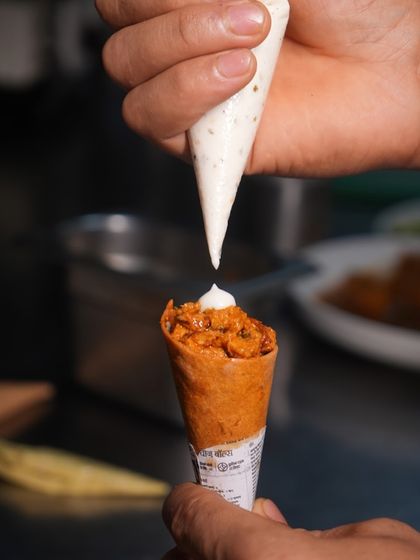 The final touch. A chef carefully pipes a creamy mousse onto our savoury cornett, adding a layer of texture and flavour that completes this signature appetizer.