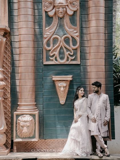 A sweet pose of a couple in traditional attire, leaning against a grand, carved wall, creating an elegant and timeless portrait.