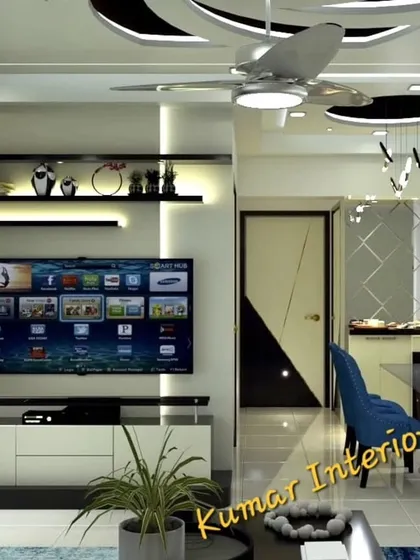 An open-plan living and dining area with a striking false ceiling design. The space includes a modern TV console, display shelves, and a compact dining set, demonstrating our expertise in space optimization for 2BHK flats.